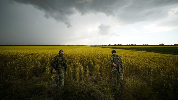 ARCHIV - 14.06.2022, Ukraine, NA: Russische Soldaten bewachen ein Gebiet neben einem Weizenfeld, w