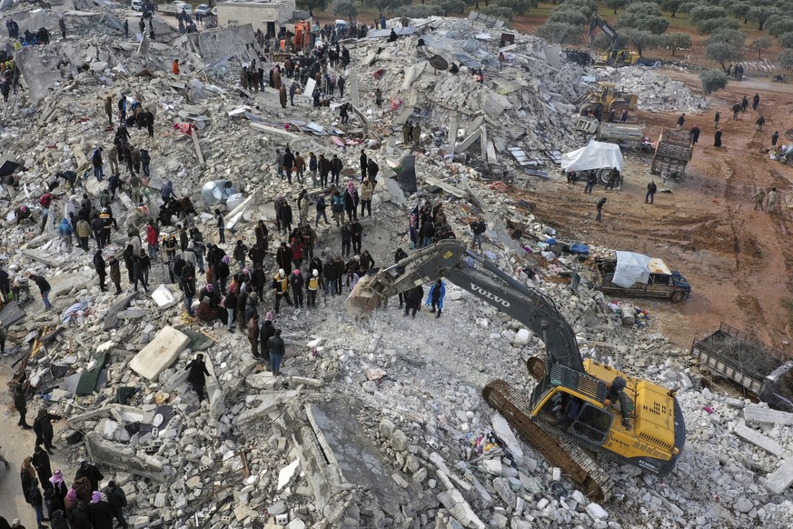 06.02.2023, Syrien, Harem: Zivilschutzmitarbeiter und Anwohner durchsuchen die Trümmer eingestürzter Gebäude nach Überlebenden, nachdem Erdbeben der Stärke 7,8 in Syrien und der Türkei Gebäude erschüt ...