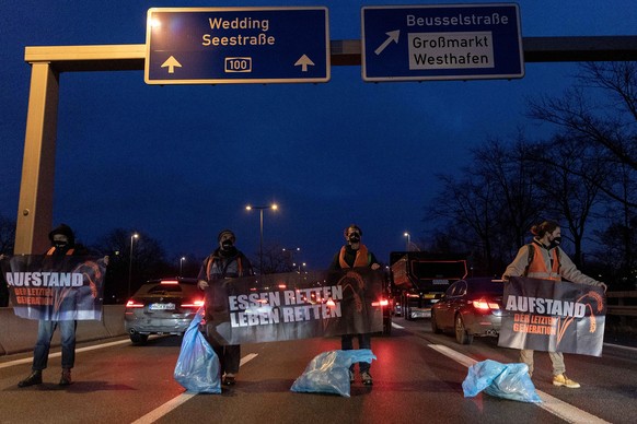 04.02.2022, Berlin: Klimaaktivisten der Gruppe �Aufstand der letzten Generation&quot; stehen auf der Fahrbahn der Autobahn A100 vor der Ausfahrt Beusselstrasse, um gegen Lebensmittelverschwendung zu p ...