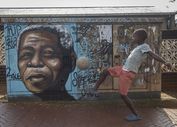 A child kicks a football in front of a mural of Nelson Mandela, in Soweto, South Africa, as the country celebrates Freedom Day. Saturday, April 27, 2024.The day marks April 27 when the country held pi ...
