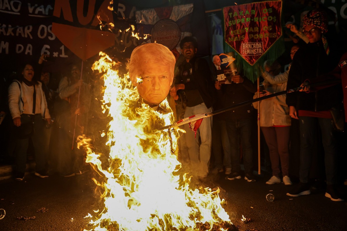 10.07.2025, Brasilien, Sao Paulo: Teilnehmer einer Demonstration gegen die von US-Präsident Trump gegen Brasilien angekündigten Zölle setzen ein Bildnis von Trump in Brand während einer Versammlung au ...