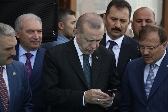 FILE - In this Friday, May 4, 2018 file photo, Turkey&#039;s President Recep Tayyip Erdogan, center, looks at his phone during a ceremony for the re-opening of the Spice Bazaar following restoration i ...