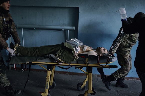 A Ukrainian soldier is wheeled on a stretcher at a hospital, in the Donetsk region, Ukraine, Monday, Dec. 19, 2022. (AP Photo/LIBKOS)