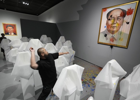 16.06.2023, Polen, Warschau: Der regimekritische Künstler Badiucao aus China wirft vor der Eröffnung einer neuen Ausstellung Farbkugeln auf sein Werk von Mao Zedong. Das Museum sah sich mit Forderunge ...