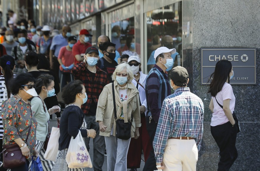ARCHIV - 08.06.2020, USA, New York: Menschen mit Masken warten im New Yorker Stadtbezirk Queens vor dem Eingang einer Bank. Das Tragen von Schutzmasken hat einer Studie zufolge in Italien und New York ...