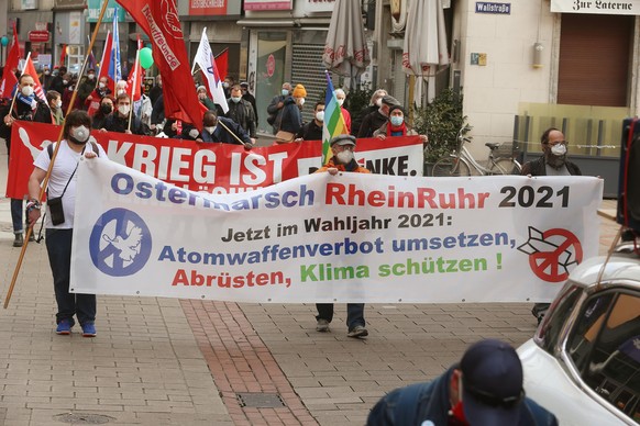 Teilnehmer marschieren beim Start des mehrtägigen Ostermarsches Rhein-Ruhr mit Plakaten, Bannern und Fahnen durch die Stadt. In vielen Städten in Nordrhein-Westfalen sind am Karsamstag, 03. April 2021 ...