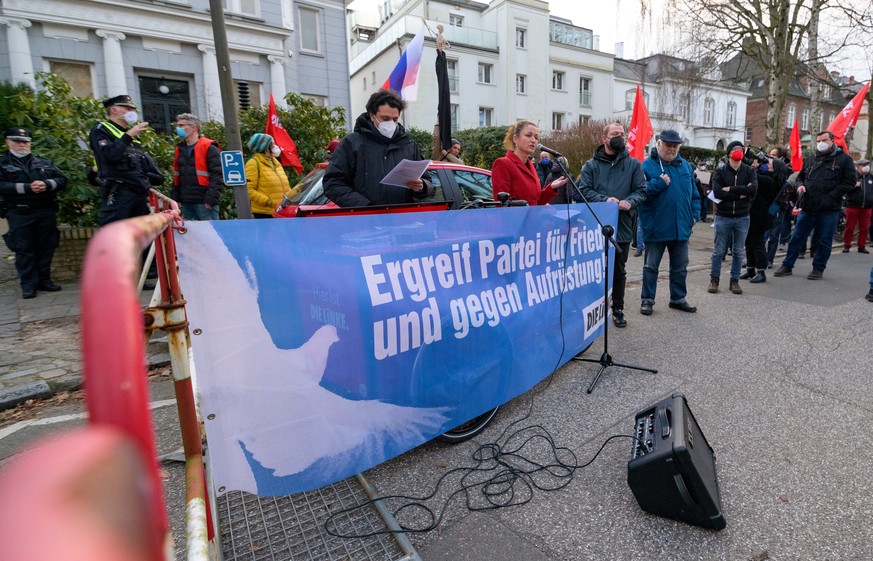 24.02.2022, Hamburg: Kundgebungsteilnehmer mit Plakaten und Fahnen stehen auf einer Stra