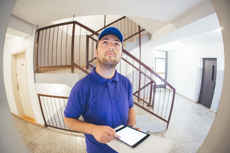 Courier in a blue uniform holding a parcel making a home delivery