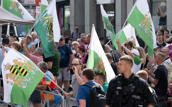 30.08.2024, Sachsen, Chemnitz: Teilnehmer einer Protestkundgebung der Partei &quot;Freie Sachsen&quot; stehen am Rande des Wahlkampfabschlusses der SPD in Chemnitz. Am 1. September finden in Sachsen d ...