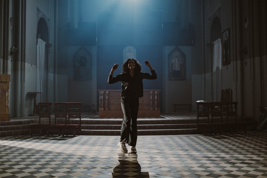 Symbolbild: Eine junge Frau tanzt ausgelassen in einer Kirche. Wie in der Politik werden Frauen auch in der Kirche anders wahrgenommen, meint Pfarrerin Angelica Dinge.