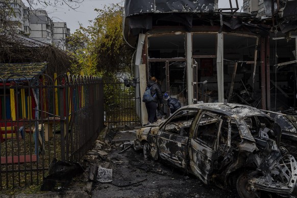25.11.2022, Ukraine, Cherson: Anwohner prüfen die Schäden an einem Geschäft, das am Vortag bei einem Angriff zerstört wurde. Unter dem Druck ukrainischer Angriffe hatten russische Truppen Cherson und  ...