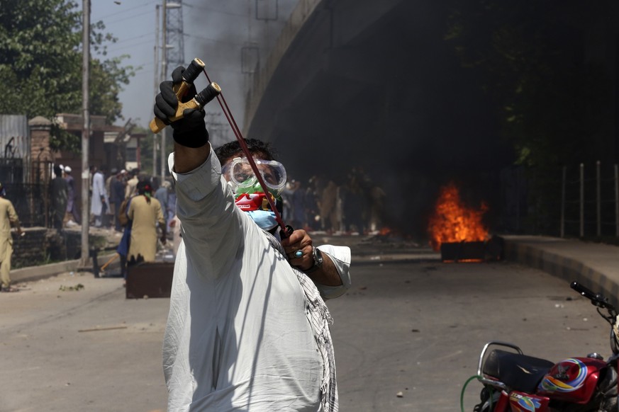 A supporter of Pakistan&#039;s former Prime Minister Imran Khan throws stones using a slingshot toward police officers during a protest against the arrest of their leader in Peshawar, Pakistan, Wednes ...