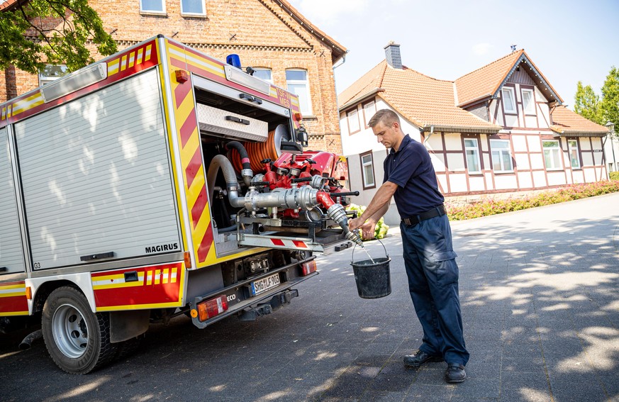 08.08.2020, Niedersachsen, Lauenau: Einsatzkräfte der Freiwilligen Feuerwehr Lauenau zapfen Löschwasser aus dem Tank eines ihrer Einsatzfahrzeuge. In der Gemeinde im Landkreis Schaumburg ist die Wasse ...