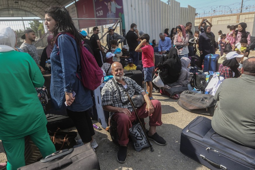 16.10.2023, Palästinensische Gebiete, Rafah: Palästinenser, einige mit ausländischen Pässen, warten am Grenzübergang Rafah auf Hilfe und eine mögliche Einreise nach Ägypten. Während Hunderttausende Pa ...