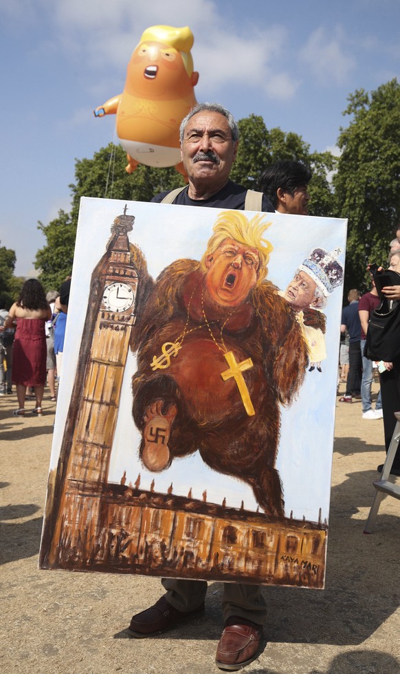 Political artist Kaya Mar holds a painting depicting Donald Trump, during protests in London, Friday, July 13, 2018. &quot;Super Callous Fragile Racist Sexist Nazi POTUS”: That placard, referencing Ma ...