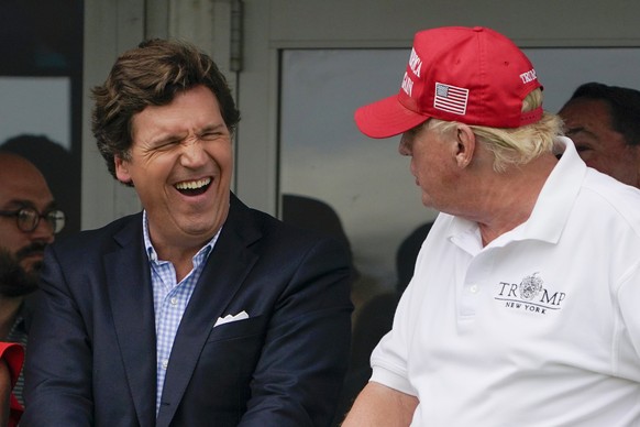 FILE - Tucker Carlson, left, and former President Donald Trump, right, react during the final round of the Bedminster Invitational LIV Golf tournament in Bedminster, N.J., July 31, 2022. A defamation  ...