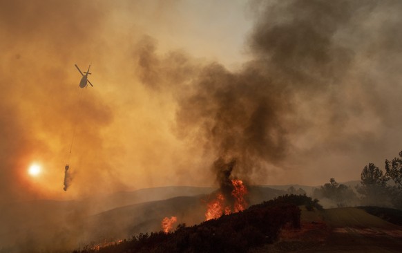 FILE - In this Sunday, Aug. 5, 2018, file photo, a helicopter drops water on a burning hillside during the Ranch Fire in Clearlake Oaks, Calif. Authorities say a rapidly expanding Northern California  ...