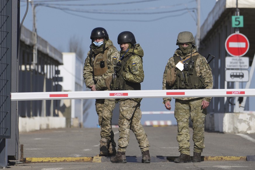 21.02.2022, Ukraine, Novotroitske: Ukrainische Grenzbeamte stehen an einem Kontrollpunkt zwischen dem von den von Russland unterst