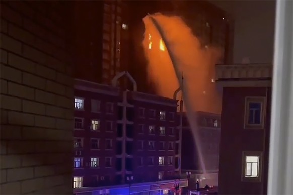 FILE - In this image taken from video, firefighters spray water on a fire at a residential building that killed several people in Urumqi in western China's Xinjiang Uyghur Autonomous Region, on Nov. 2 ...