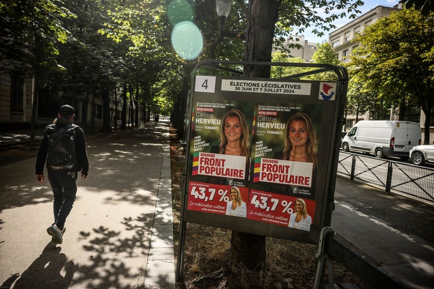 06.07.2024, Frankreich, Paris: Ein Mann geht in Paris an Wahlkampfschildern für die bevorstehenden Parlamentswahlen vorbei. Der zweite Wahlgang begann am Samstag im Ausland, und die Wahlen enden am So ...