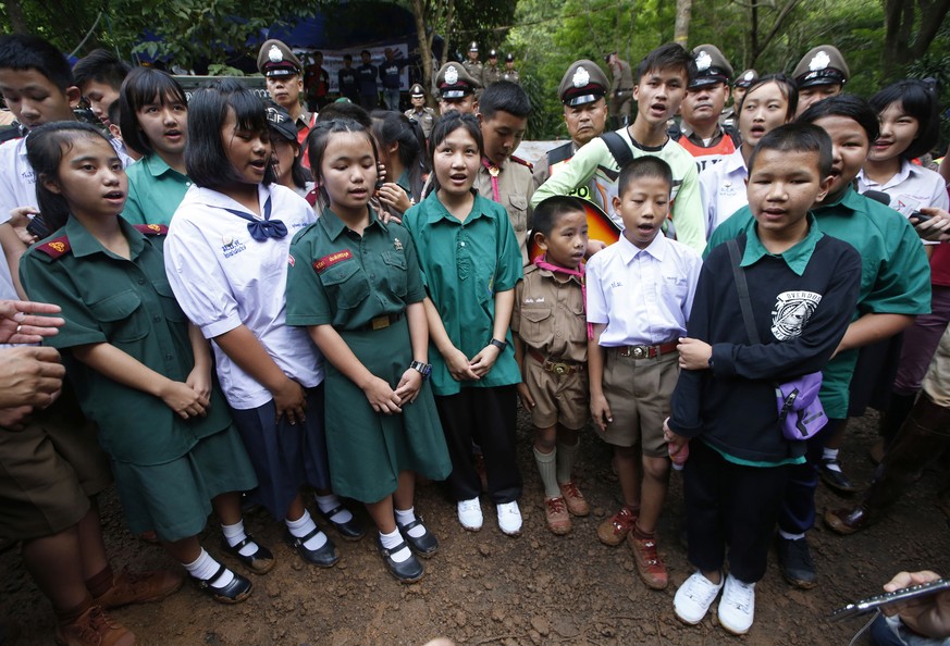 Friends sing a song outside of a cave complex where 12 boys and their soccer coach are trapped inside, in Mae Sai, Chiang Rai province, in northern Thailand, Wednesday, July 4, 2018. The Thai soccer t ...