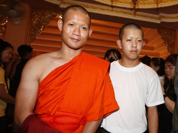 Pornchai Kamluang, right, a member of Wild Boars soccer team, walks with Buddhist monk, former soccer coach Ekkapol Chanthawong, after the completion of their serving as novice Buddhist monks, followi ...
