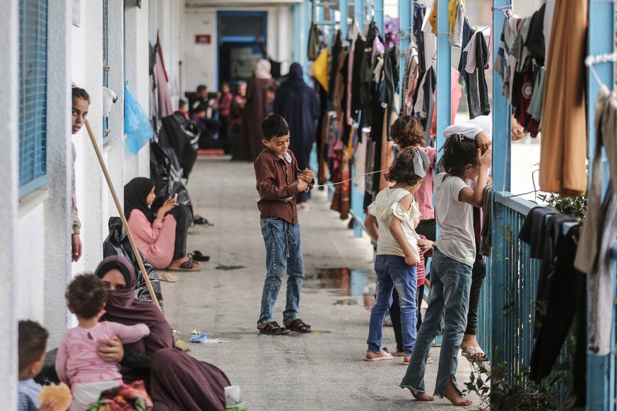 14.10.2023, Palästinensische Gebiete, Khan Yunis: Palästinenser, die vor den israelischen Angriffen aus ihren Häusern geflohen sind, finden Zuflucht in einer von den Vereinten Nationen geführten Schul ...