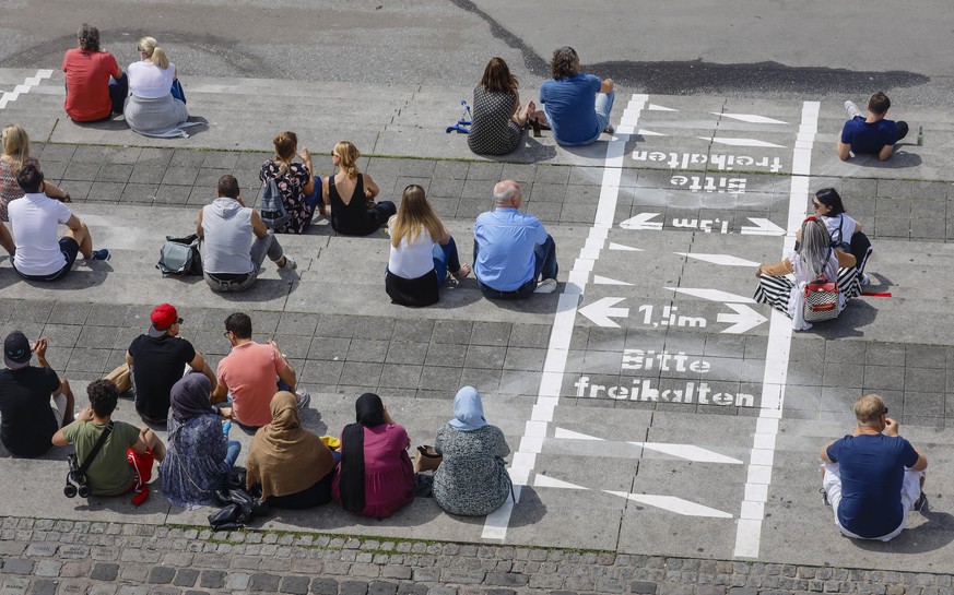 18.07.2020, Duesseldorf, Nordrhein-Westfalen, Deutschland - Rheinuferpromenade in Zeiten der Corona-Pandemie, auf der Rheintreppe am Burgplatz sitzen Menschen neben gemalten Linien fuer soziale Distan ...