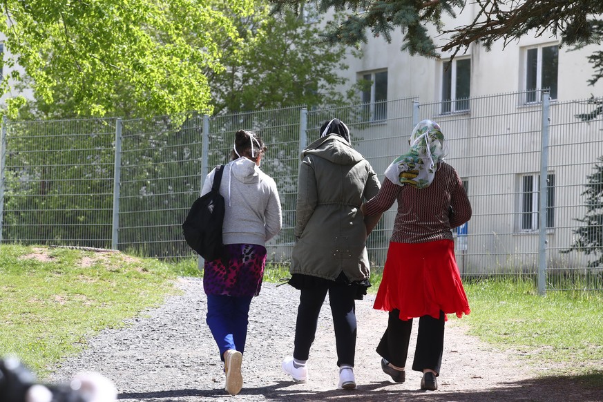 Asylbewerber gehen auf dem Gelände der Erstaufnahmeeinrichtung des Landes Thüringen spazieren.