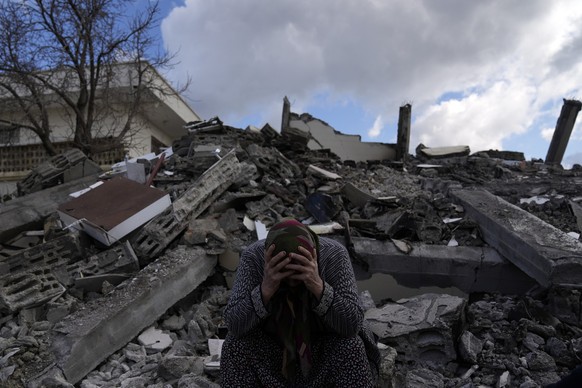 07.02.2023, Türkei, Osmaniye: Eine Frau sitzt auf Trümmern, nach dem verheerenden Erdbeben. Mehr als 13 Millionen Menschen in der Türkei sind nach Einschätzung der Regierung von der Erdbebenkatastroph ...