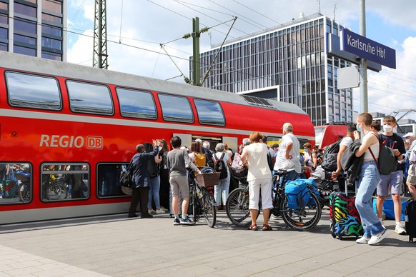 Fahrgäste warten in einer Schlange am Bahnsteig des Karlsruher Hauptbahnhofs auf den Einstieg in den Regionalexpress. Seitdem man das 9-Euro-Ticket kaufen kann, bilden sich große Menschentrauben an de ...