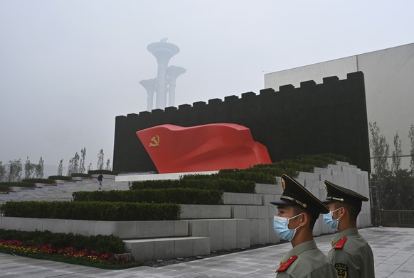 BEIJING, CHINA - JUNE 25: Chinese police officers stand in front of a monument with a Communist Party flag outside the newly built Museum of the Communist Party of China on June 25, 2021 in Beijing, C ...