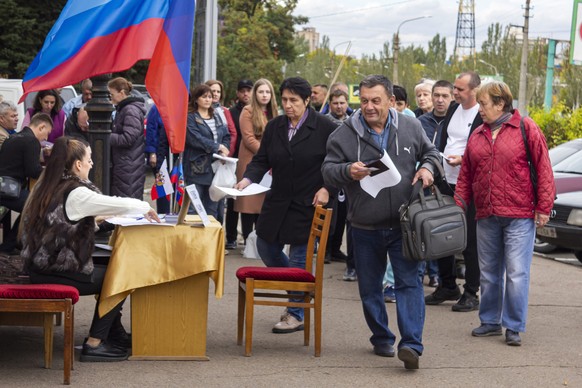 24.09.2022, Ukraine, Luhansk: Menschen stellen sich in einer Reihe auf, um an einem Scheinreferendum teilzunehmen. Der Kreml geht bei den Scheinreferenden in den besetzten ukrainischen Gebieten von ei ...