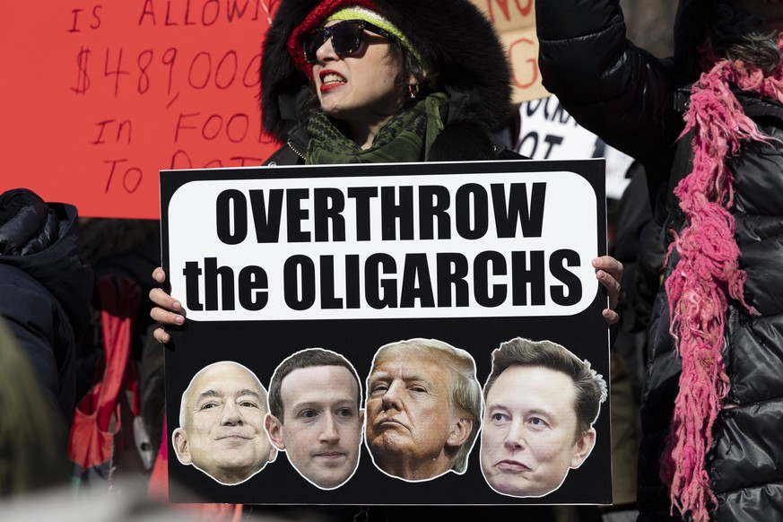 February 17, 2025, New York, New York, USA: A demonstrator chants and holds a sign that reads OVERTHROW the OLIGARCHS with images of Bezos, Zuckerberg, President Trump &amp; Musk. Thousands of anti-Tr ...