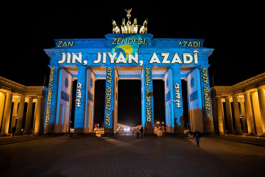 13.12.2022, Berlin: Das Brandenburger Tor wird bei einer Protestaktion für Solidarität mit den Protesten im Iran mit dem persischen Schriftzug «Zan - Zendegi - Azadi» («Frau - Leben - Freiheit») anges ...