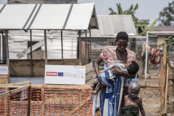 19.08.2024, Demokratische Republik Kongo, Munigi: Eine Frau geht mit ihren an Mpox erkrankten Kindern nach einer Behandlung. Der Kongo wird nächste Woche die ersten Impfstoffdosen aus den Vereinigten  ...