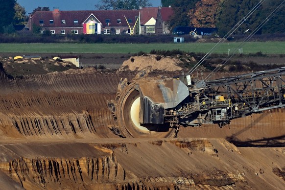 ARCHIV - 19.10.2022, Nordrhein-Westfalen, Jüchen: Ein Schaufelradbagger arbeitet im Braunkohletagebau Garzweiler. Im Hintergrund ist die Ortschaft Lützerath zu sehen. Der Kohleausstieg im Rheinischen  ...