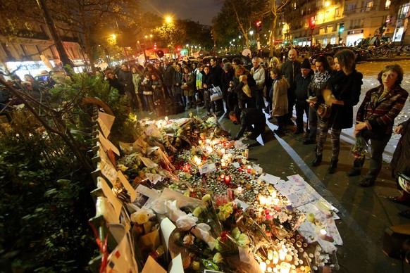 ARCHIV - 16.11.2015, Frankreich, Paris: Trauernde Menschen z�nden am 16.11.2015 vor dem Bataclan Theater in Paris (Frankreich) Kerzen an und legen Blumen nieder. Bei einer Serie von Terroranschl�gen i ...