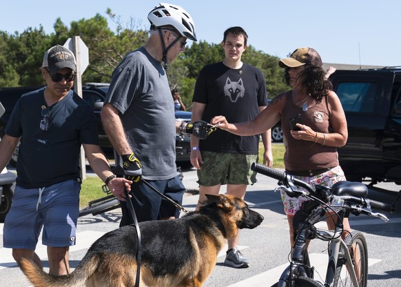 President Joe Biden stands with his dog Commander as he talks with a woman at Gordons Pond in Rehoboth Beach, Del., Saturday, June 18, 2022. Earlier Biden fell as he tried get off his bike to greet a  ...
