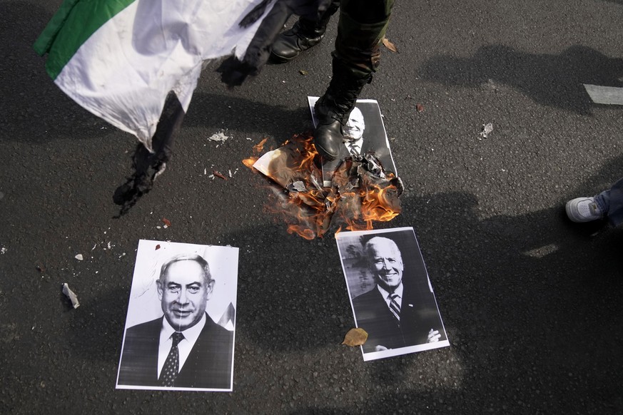 20.10.2023, Indonesien, Jakarta: Ein Demonstrant tritt während einer pro-palästinenschen Demonstration vor der US-Botschaft auf ein brennendes Porträt von US-Präsident Biden, das neben einem Porträt d ...