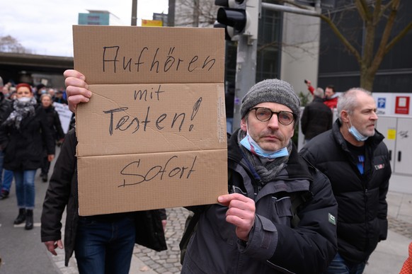 13.03.2021, Sachsen, Dresden: Ein Demonstrant h�lt w�hrend einer Kundgebung ein Schild mit der Aufschrift &quot;Aufh�ren mit dem Testen. Sofort&quot;. Obwohl die in Dresden geplante Demonstration von  ...