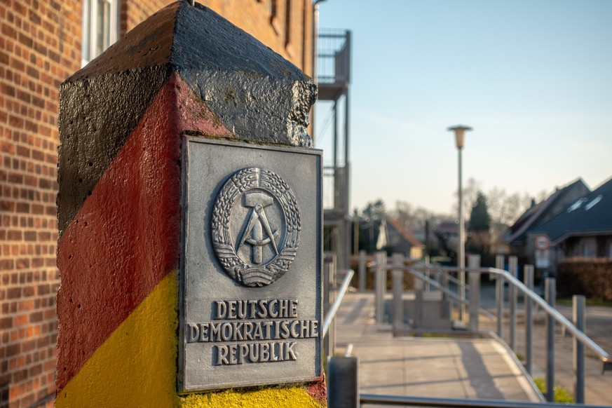 a pole with the coat of arms of the GDR stands in a village