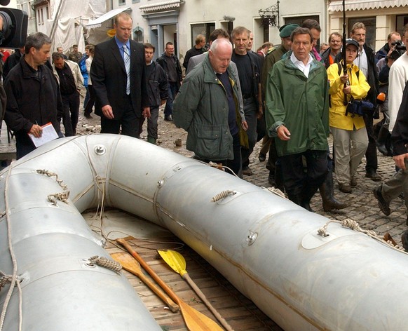 Grimma (Sachsen): Bundeskanzler Gerhard Schröder (r) und der sächsische Ministerpräsident Georg Milbradt (l) gehen am 14.08.2002 in der verschlammten Innenstadt von Grimma (Sachsen) an einem Rettungsb ...