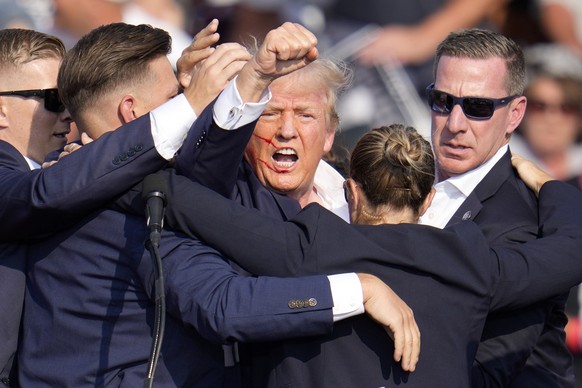 Republican presidential candidate former President Donald Trump is helped off the stage by U.S. Secret Service agents at a campaign event in Butler, Pa., on Saturday, July 13, 2024. (AP Photo/Gene J.  ...