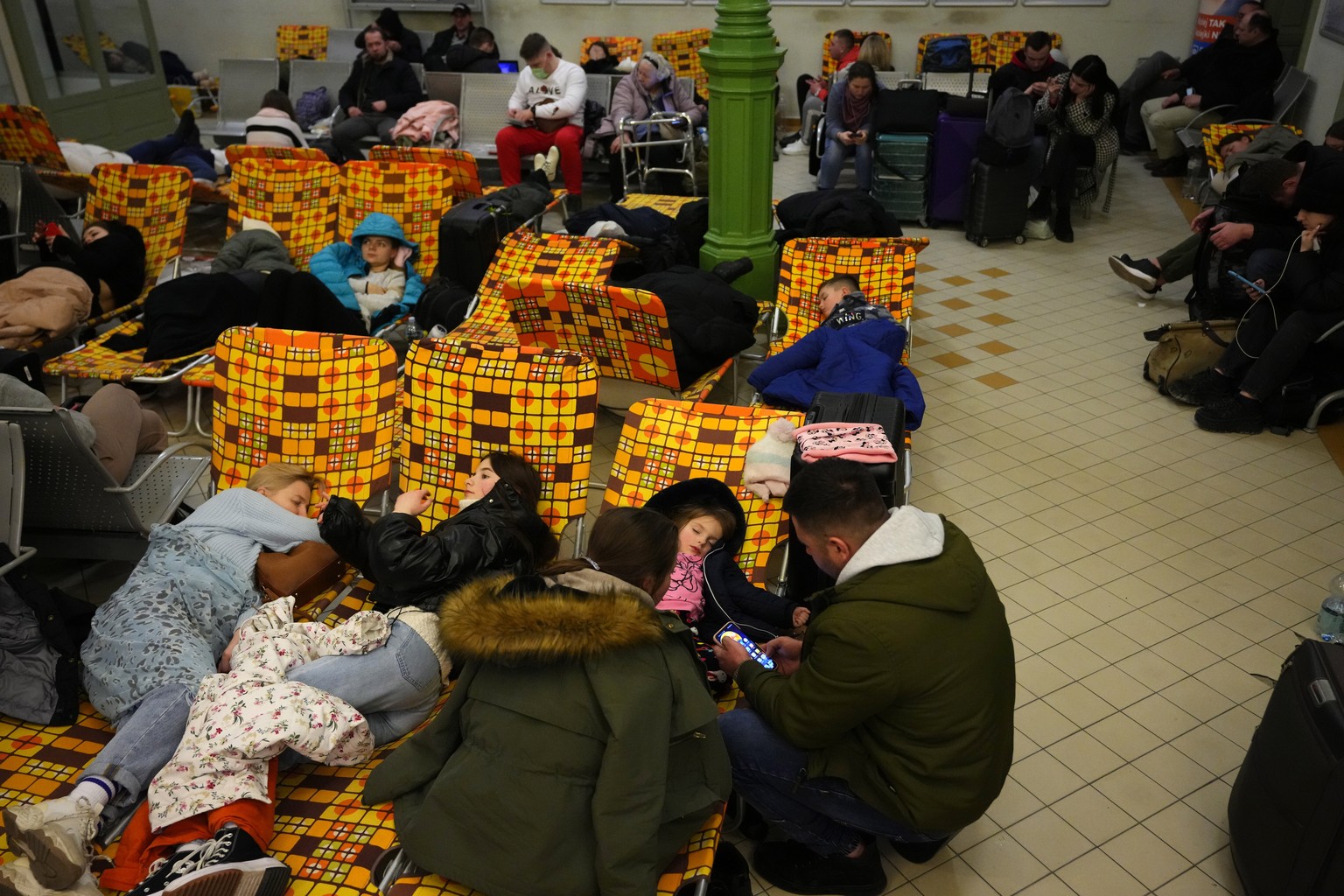 People from neighboring Ukraine, rest at a train station that was turned into an accommodation center in Przemysl, Poland, on Thursday, Feb. 24, 2022. Russia launched a wide-ranging attack on Ukraine  ...