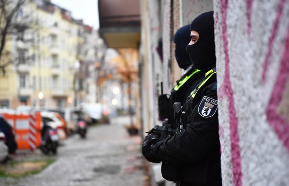 ARCHIV - 23.11.2023, Berlin: Polizeibeamte stehen bei einer Razzia in Berlin-Friedrichshain am Eingang eines Gebäudes. Sicherheitskräfte hatten im November 2023 im Zusammenhang mit dem Verbot der Terr ...