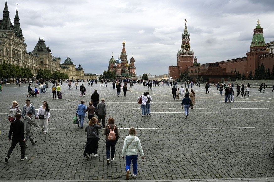 People walk in Red Square with the GUM department store, left, the St. Basil&#039;s Cathedral, the Spasskaya Tower and the Kremlin Wall, right, in Moscow, Russia, Wednesday, July 12, 2023. (AP Photo/A ...