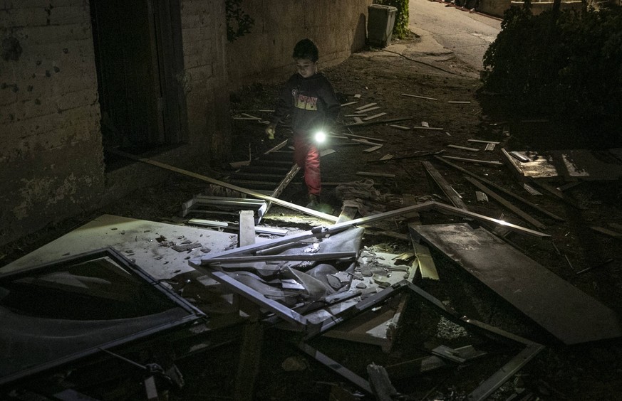 231010 -- JERUSALEM, Oct. 10, 2023 -- A kid walks through the debris of buildings damaged by rockets in the village of Abu Gosh, west of Jerusalem, Oct. 9, 2023. MIDEAST-JERUSALEM-ROCKET ATTACK ChenxJ ...