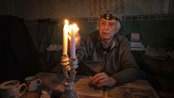 28.12.2022, Ukraine, Kupjansk: Ein Rentner zündet Kerzen in seinem Haus an, nachdem er mehr als vier Monate ohne Strom gelebt hat. Foto: Evgeniy Maloletka/AP/dpa +++ dpa-Bildfunk +++