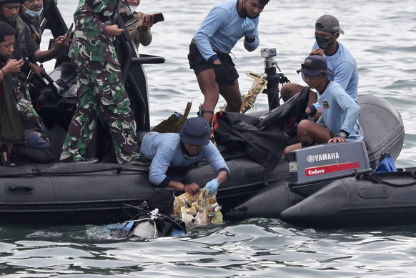Taucher der indonesischen Marine ziehen während einer Suchaktion ein Flugzeugteil aus dem Wasser.